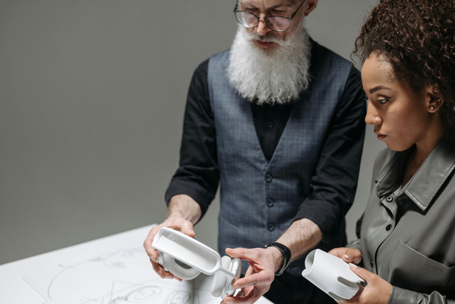 Senior adult and young woman collaborating on headphone design project indoors.